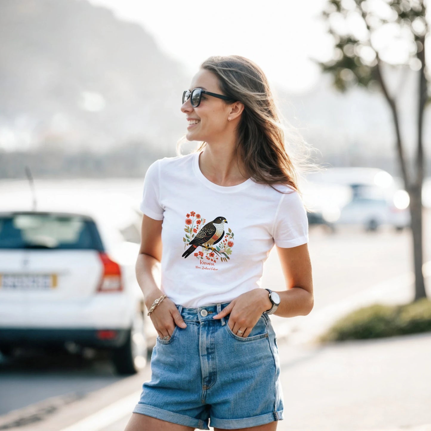 Woman wearing a white t-shirt with a Karearea NZ Falcon – 2025 Bird of the Year design outdoors