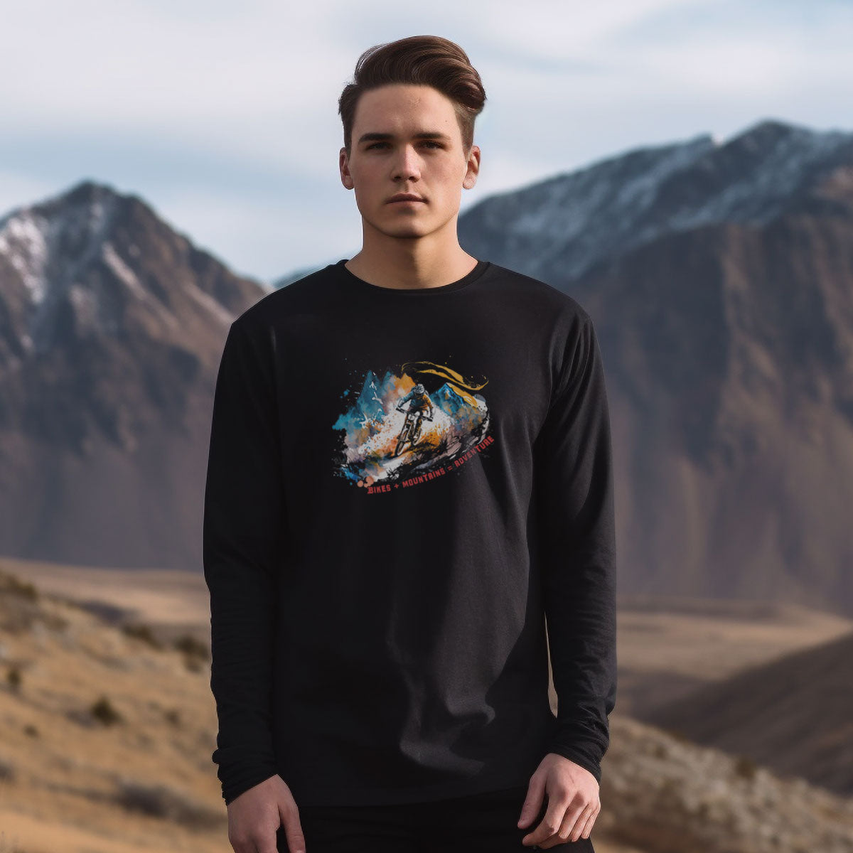 guy in the mountains wearing a black long sleeve t-shirt with a mountain bike print with the caption bikes + mountains = adventure