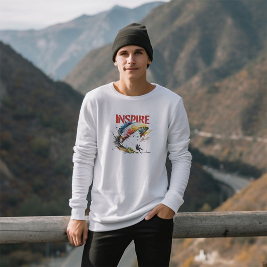 guy in the mountains wearing a white long sleeve t-shirt with a paraglider graphic and Inspire caption