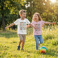 Two young children running and laughing outdoors while wearing colourful Animal Alphabet A–Z T-shirts.