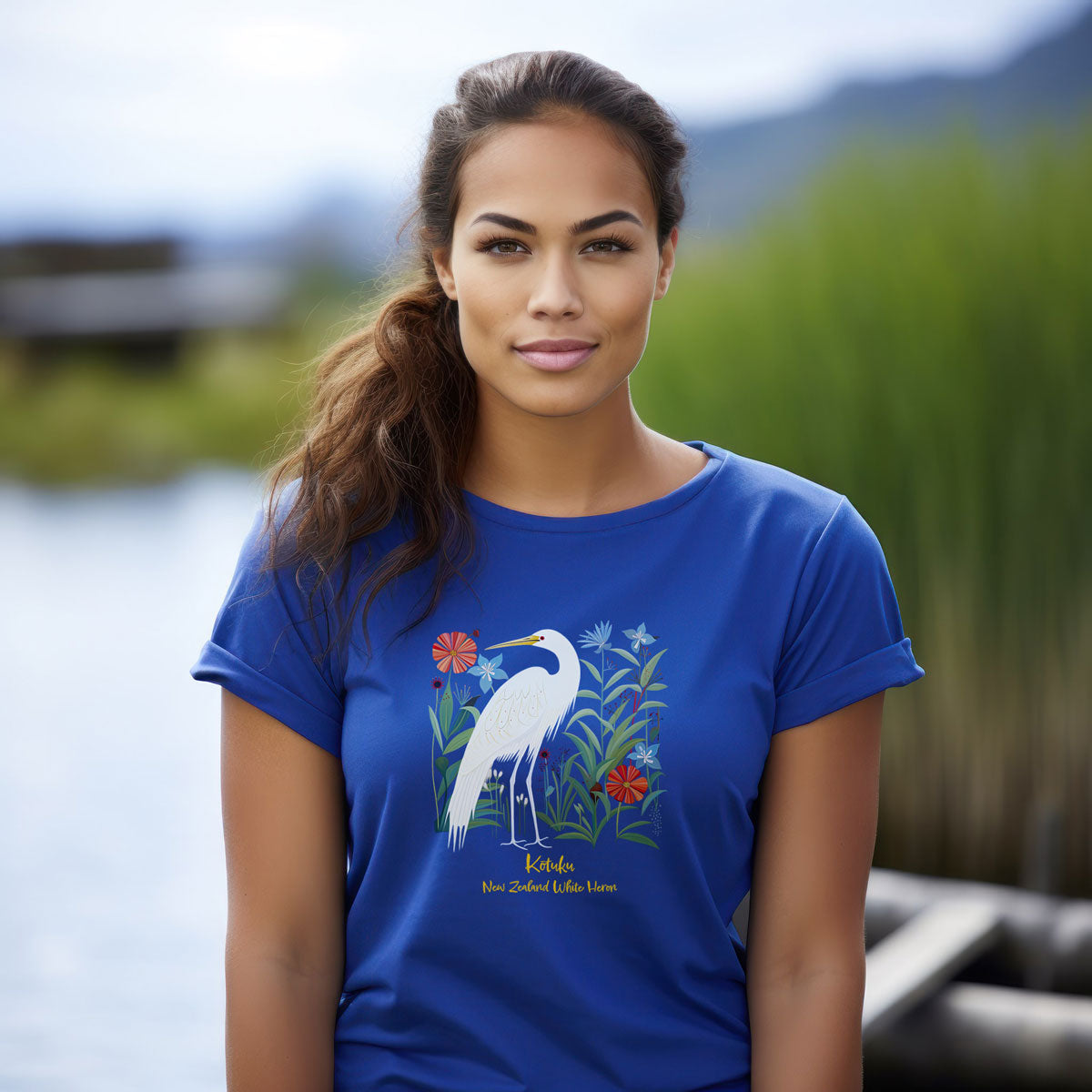 young woman wearing a royal blue t-shirt with a New Zealand Kōtuku white heron print