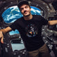 guy floating in the space station wearing a black t-shirt with a spaceman playing the drums