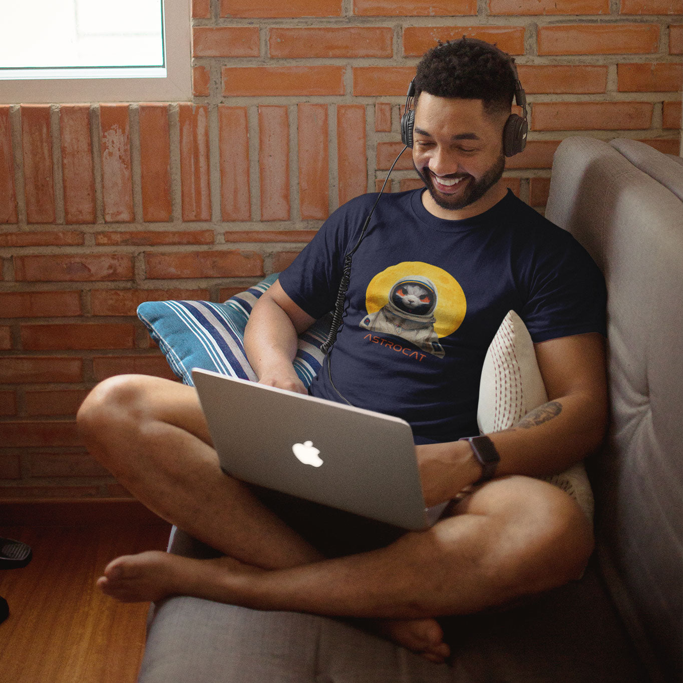A guy listening to music wearing a navy t-shirt with an Astrocat print on the front