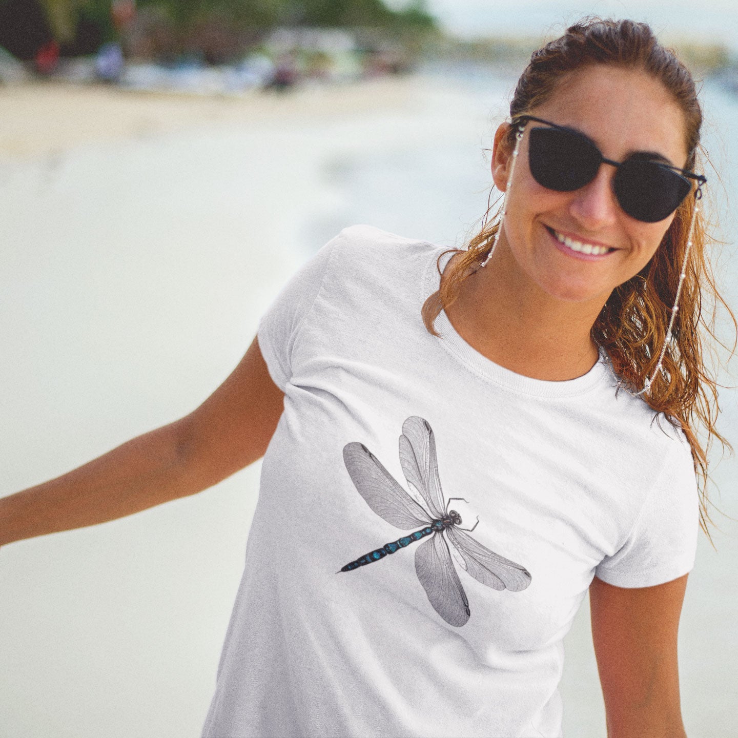 woman on the beach wearing a white t-shirt with a dragonfly print