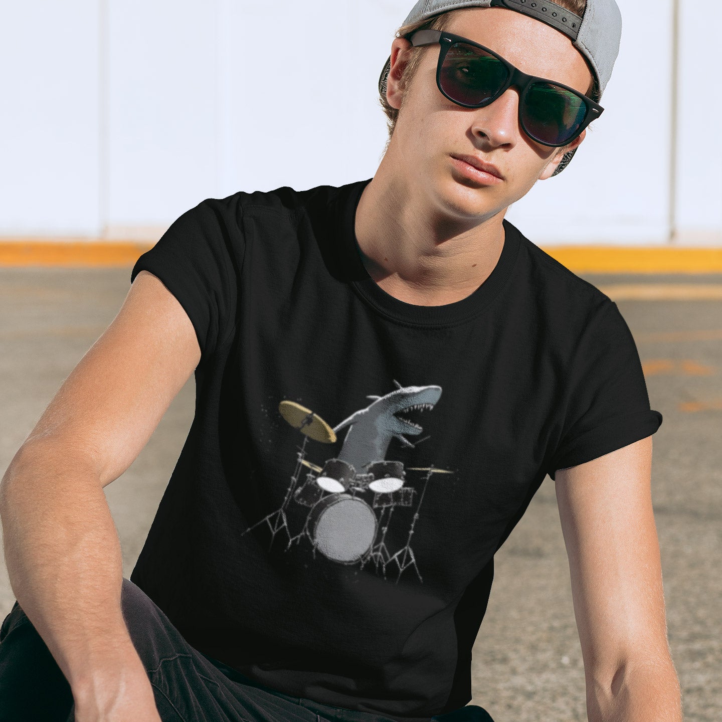 A man wearing a black t-shirt with a shark playing drums illustration