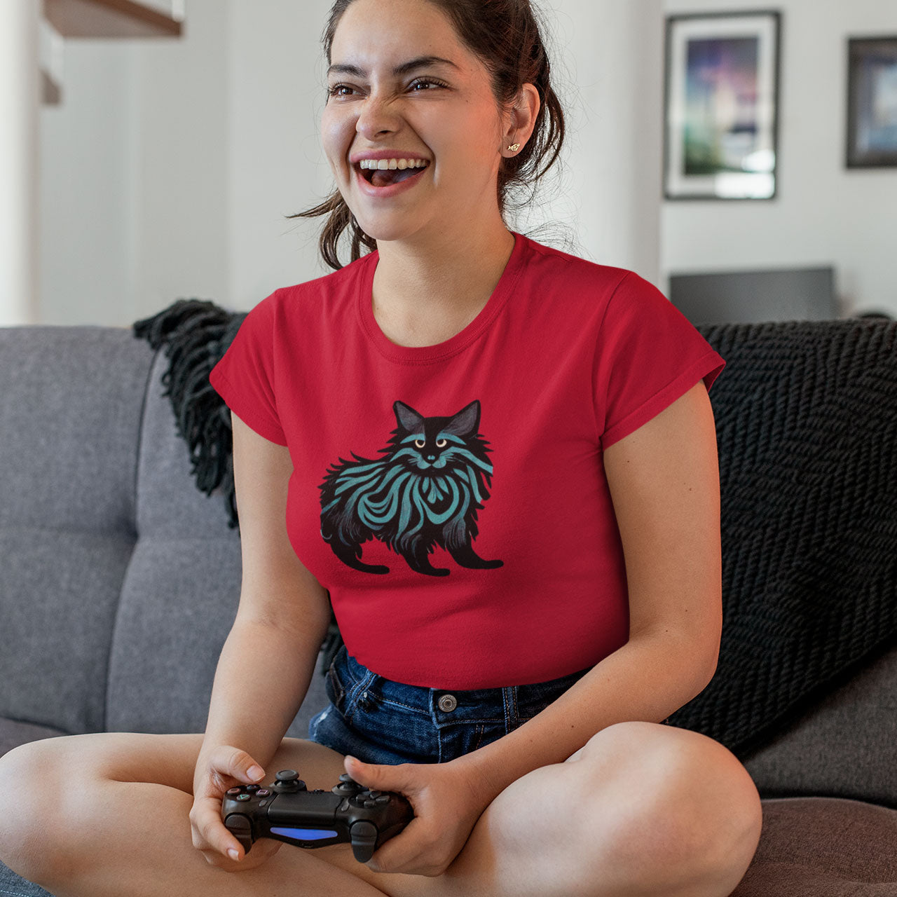 Girl on a couch playing playstation wearing a red t-shirt with a Maine Coon cat print