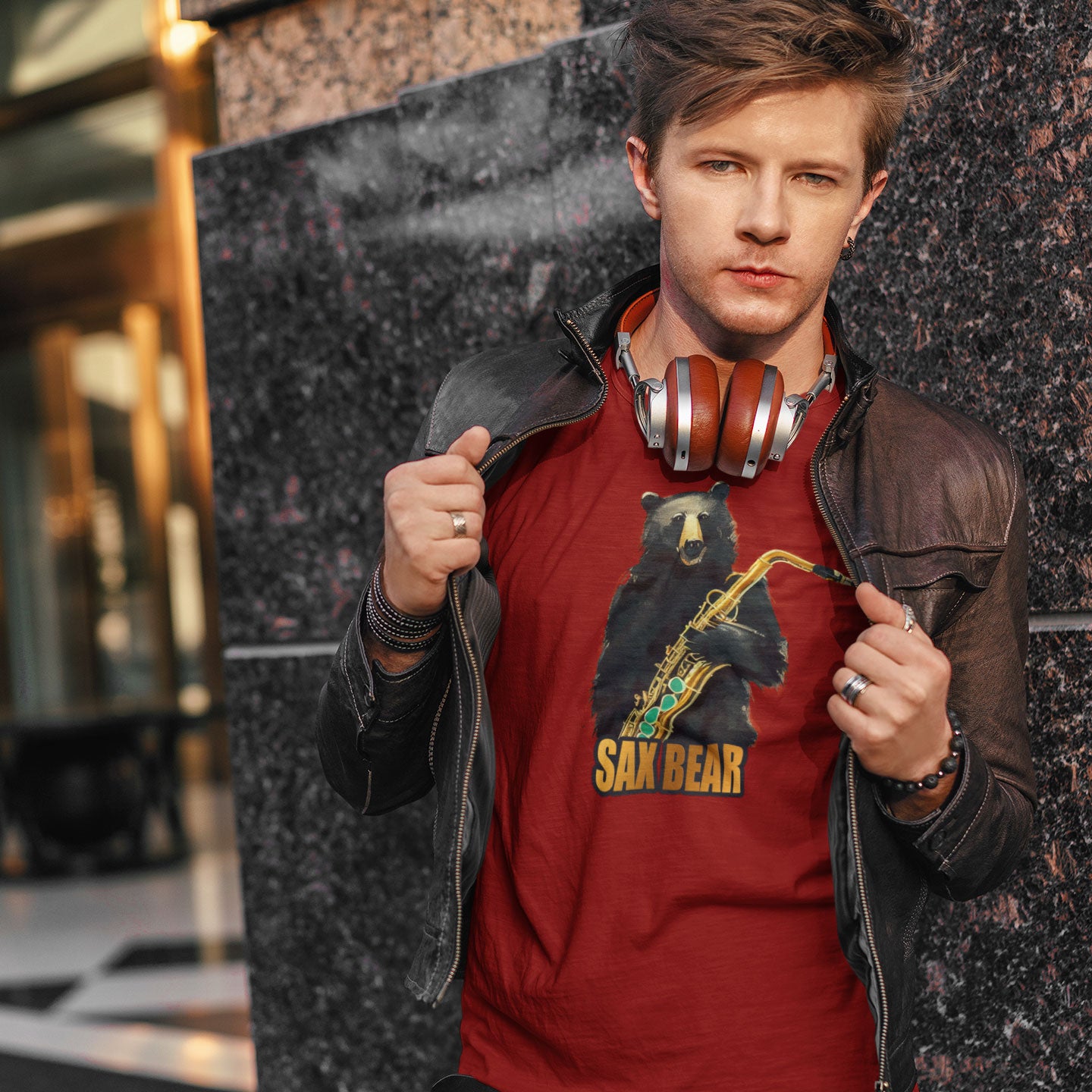 Young guy wearing headphones and a red t-shirt with a print of a bear holding a saxophone with the caption Sax Bear