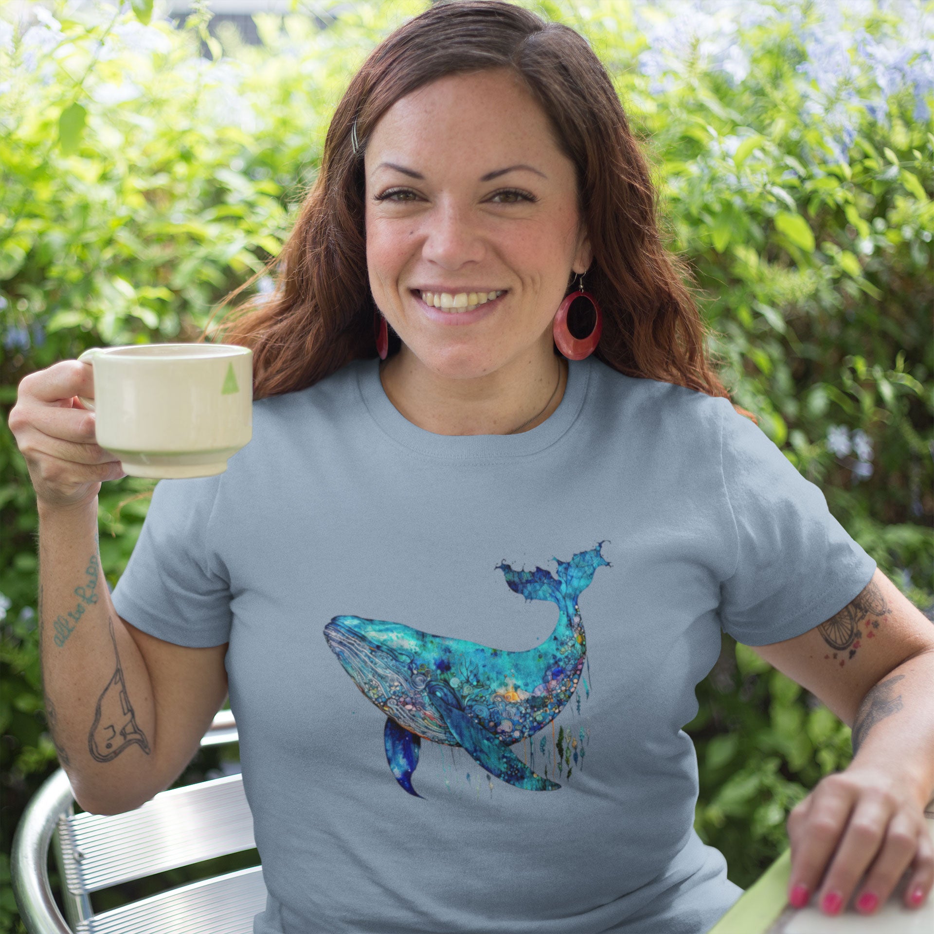 woman drinking coffee wearing a light blue t-shirt with a blue whale print