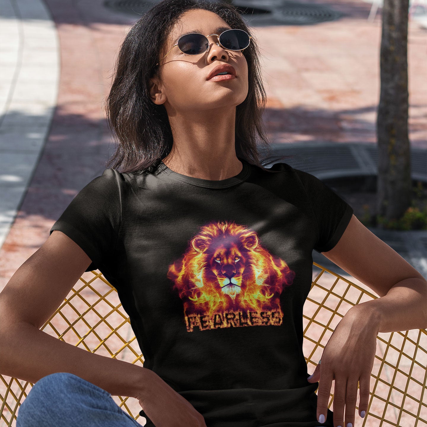 woman sitting in the sun wearing a black t-shirt with a flaming lion and fearless caption print