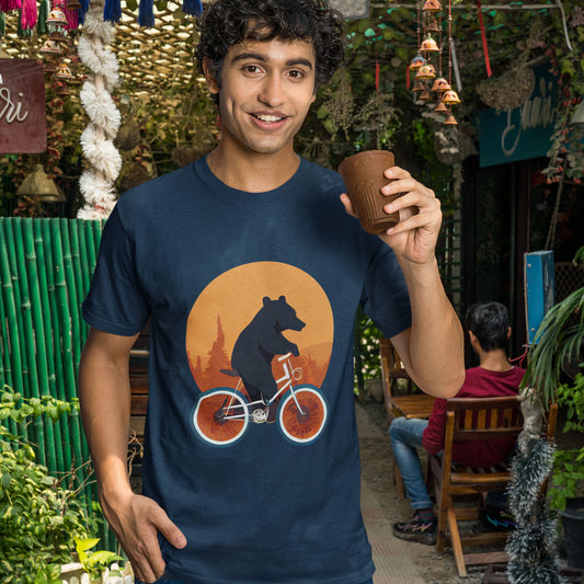 A guy having a drink wearing a navy t-shirt with a bear riding a bike print