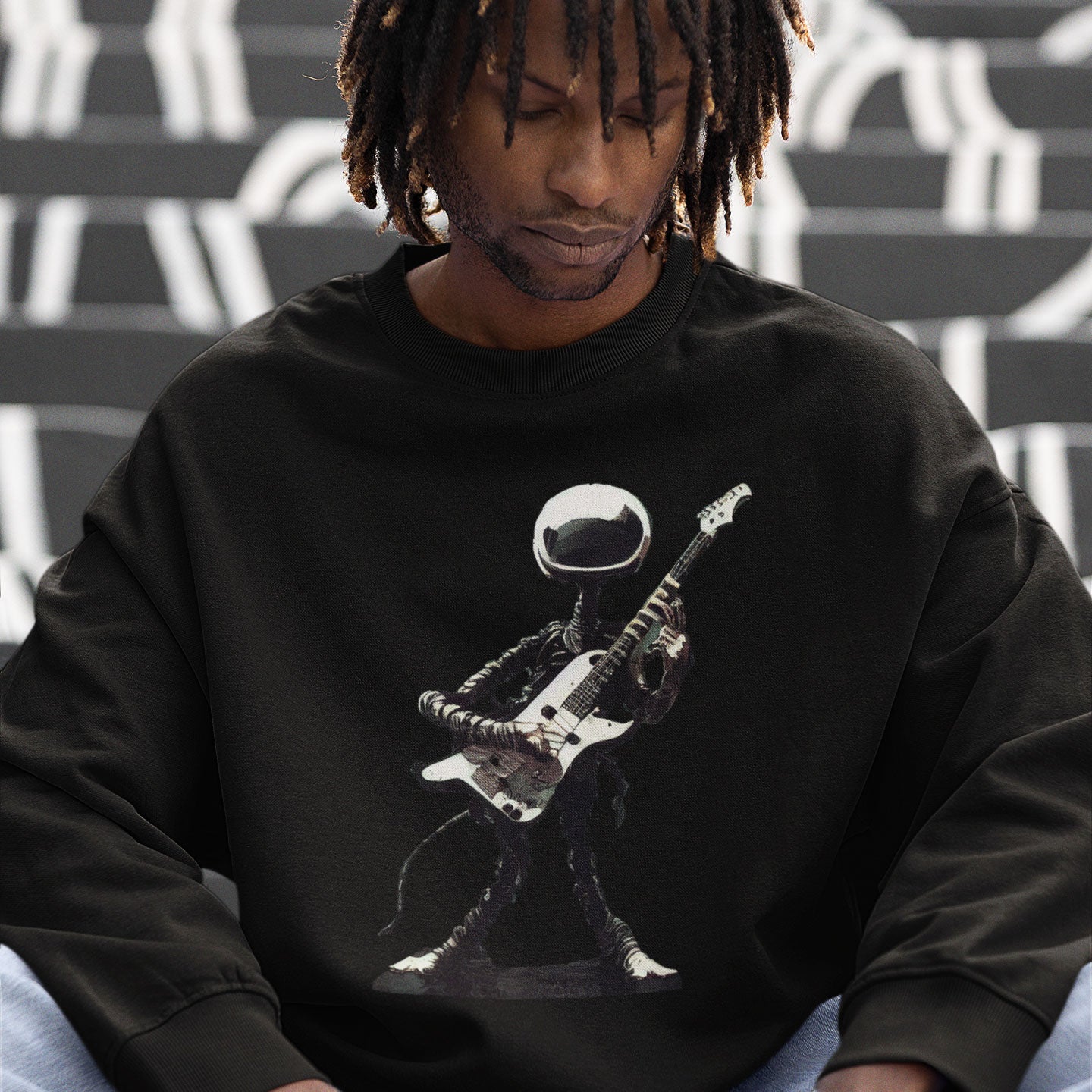 A man wearing a black sweatshirt with an alien playing a guitar print