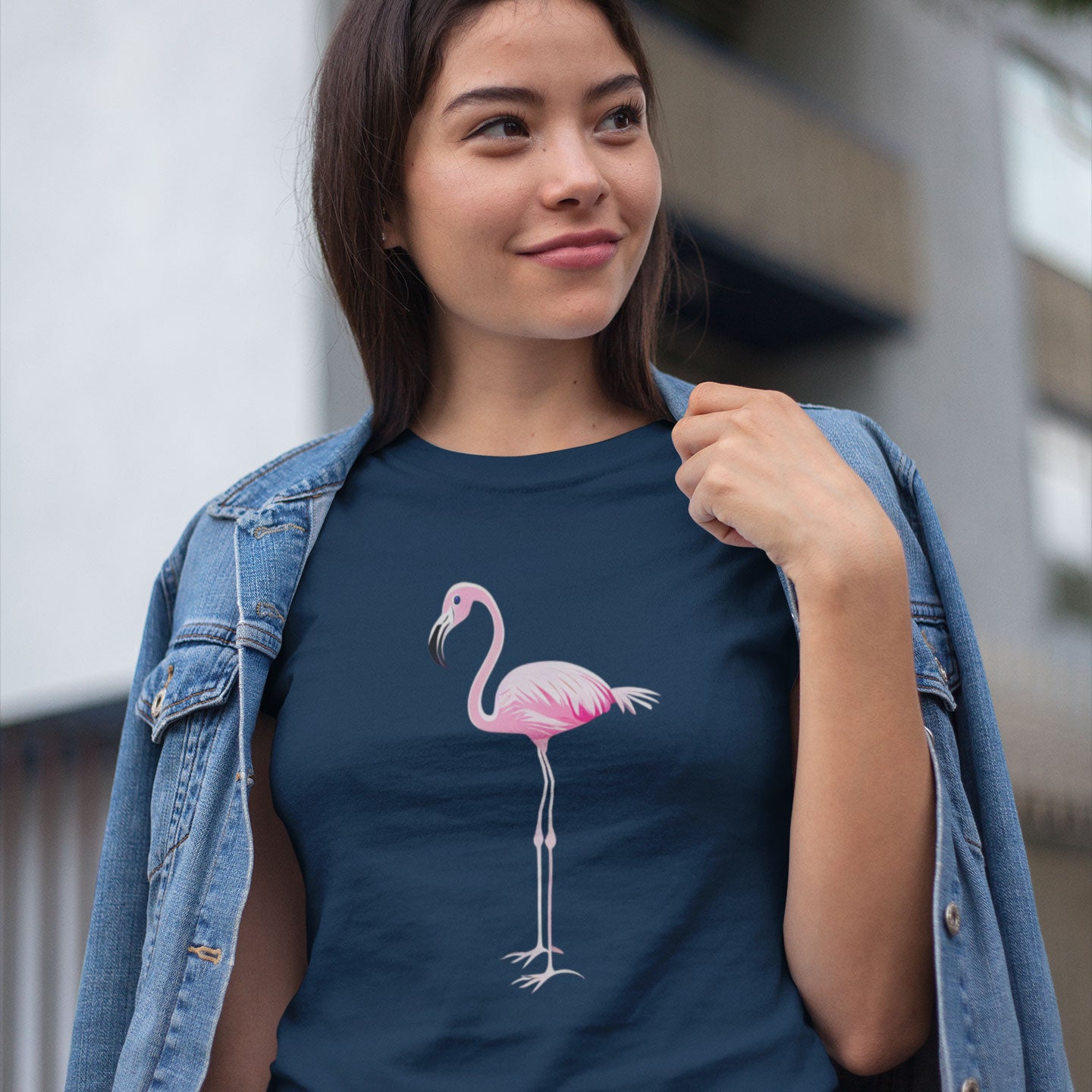 a woman wearing a denim jacket over a navy blue t-shirt with a pink flamingo print