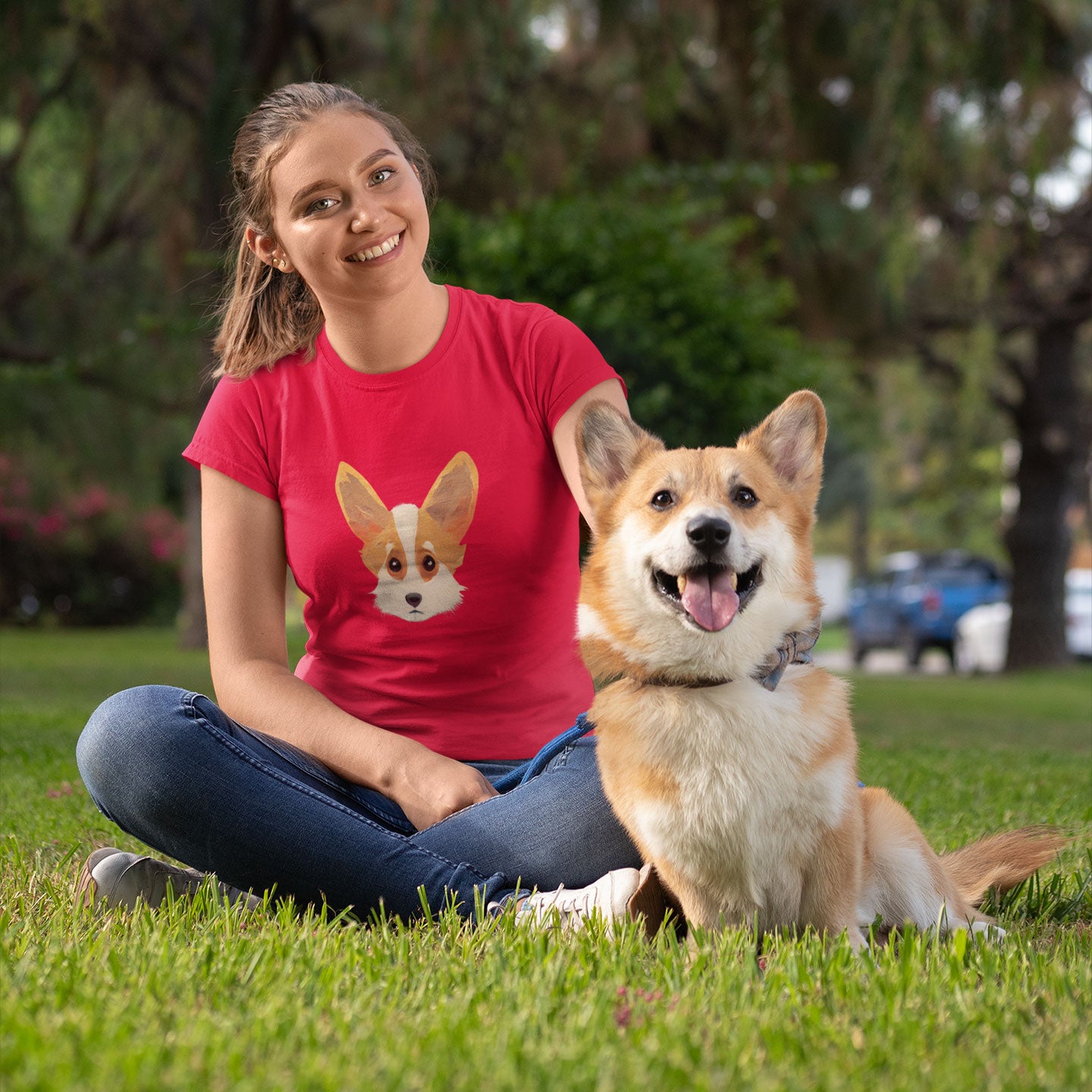Woman and corgi dog sitting on the grass wearing a red t-shirt with a cute corgi print