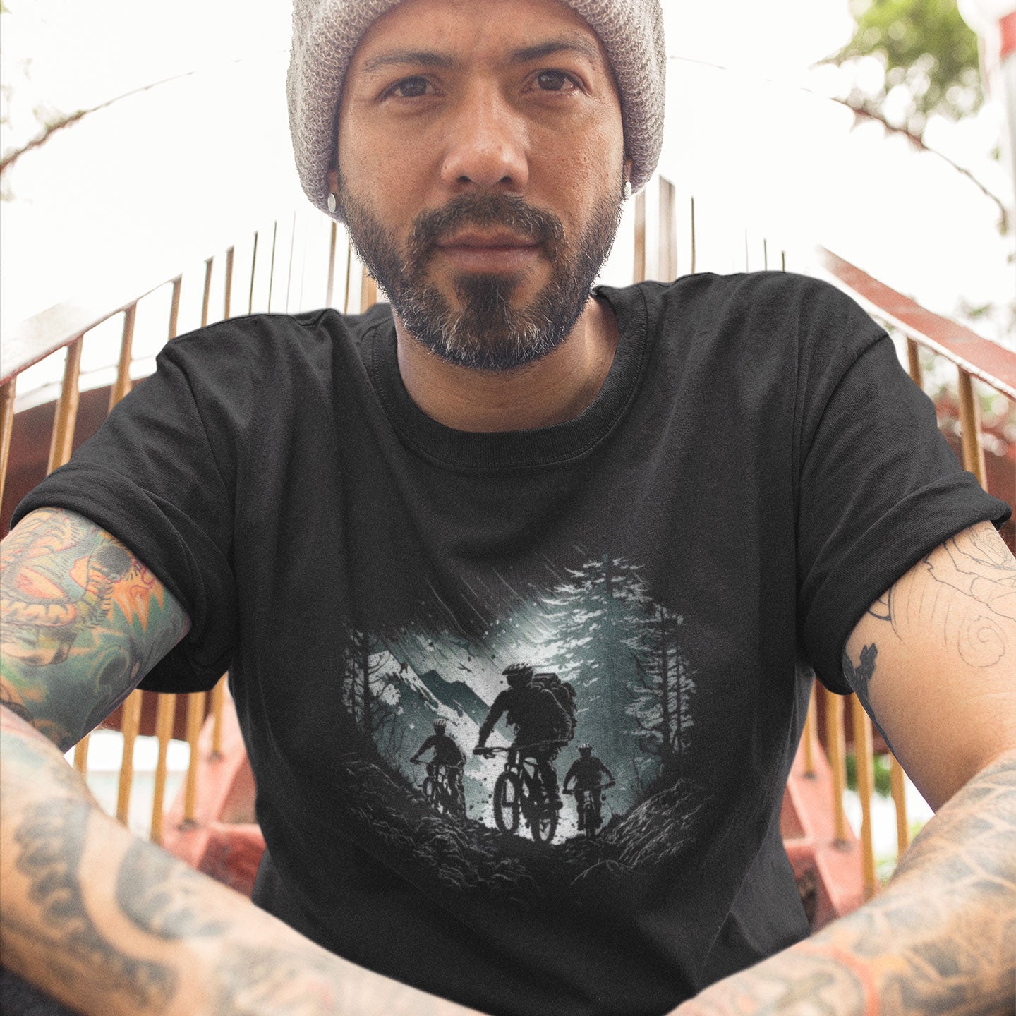 Tattooed man wearing a black t-shirt with a mountain bike print 