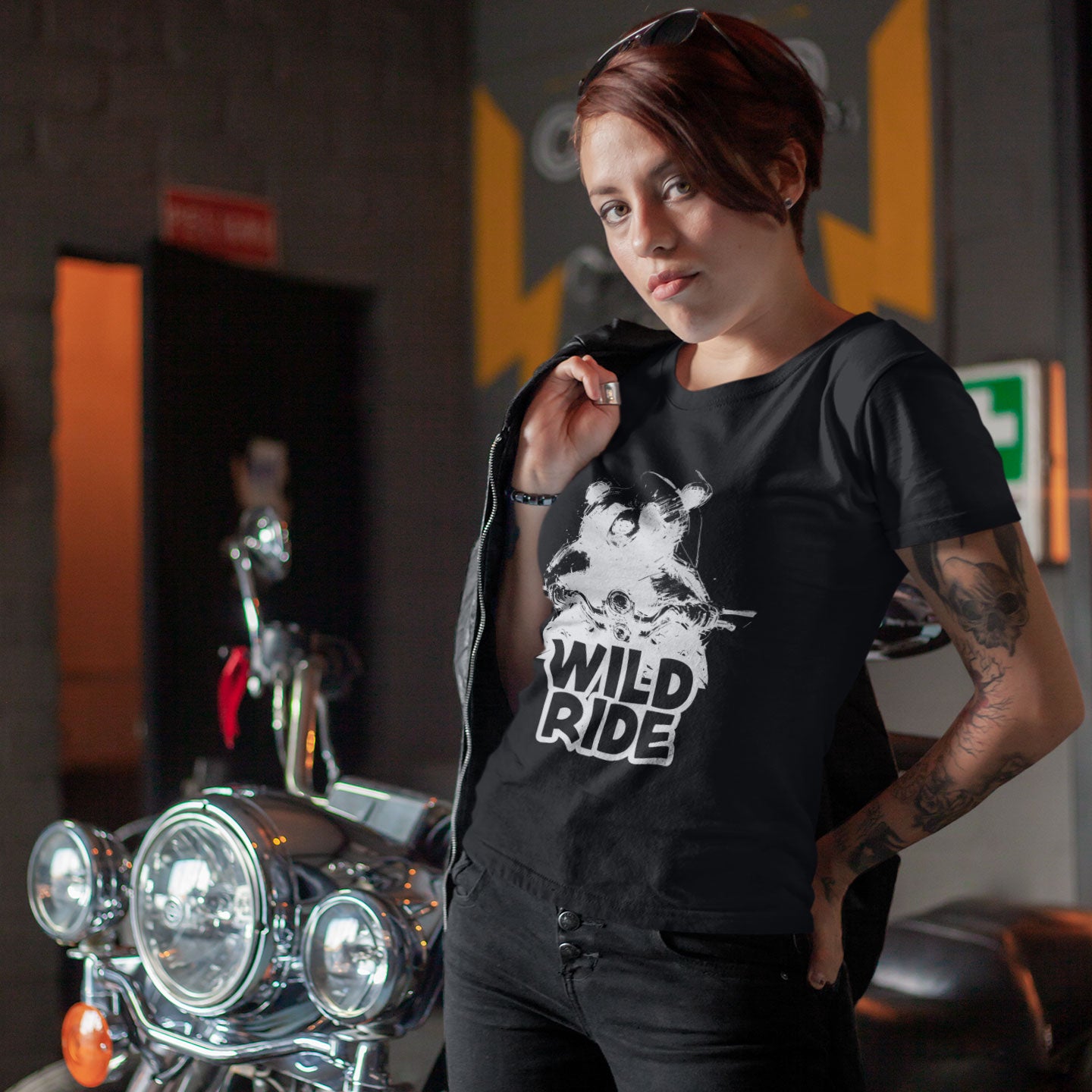 Woman standing by motorcycle wearing a black t-shirt with a bear on a bike with Wild Ride caption